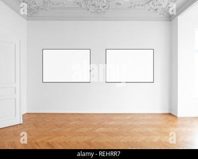 two blank picture frames hanging on white wall in empty room Stock Photo