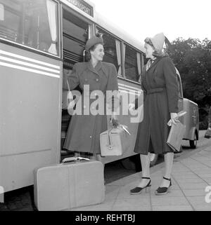 Women's fashion in the 1940s. A young woman in a typical 1940s coat, with matching hat, shoes, gloves and handbag. She steps off the bus carrying her luggage and is greeted by a lady friend also in a typical 1940s coat. Photo Kristoffersson Ref V77-4. Sweden 1947 Stock Photo