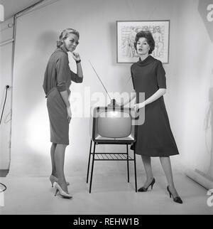 Television in the 1950s. Two young women are standing dressed in a typical 50s dress beside a televison set with an table antenna on top of it. In 1952 1.4 million households in Britain had a television.  Photo Kristoffersson ref BZ26. Sweden 1952 Stock Photo