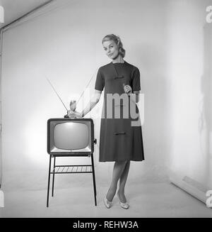 Television in the 1950s. A young woman is standing dressed in a typical 50s dress beside a televison set with an table antenna on top of it. In 1952 1.4 million households in Britain had a television.  Photo Kristoffersson ref BZ26. Sweden 1952 Stock Photo