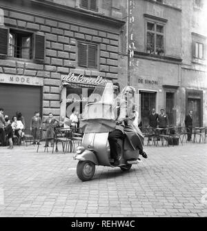 Couple in Italy in the 1950s. A young couple on a Vespa scooter driving on a street in Milan Italy 1950. Photo Kristoffersson Ref AY24-2 Stock Photo