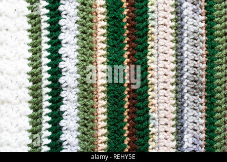 Closeup of an afghan crocheted from acrylic yarn with colors of the changing seasons, from winter into spring. Stock Photo