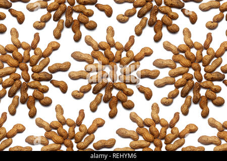 A collection of unrefined peanut nuts lie in the shape of a circle or sun on an isolated white background with a clipping path. Raw Peanut Pattern Stock Photo