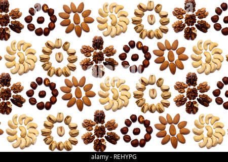 A collection of nuts made from almonds, walnuts, hazelnuts, pistachios, cashews lie in the shape of a circle or the sun on an isolated white backgroun Stock Photo