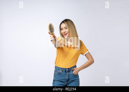 young beautiful woman combing her hair isolated over grey background. Stock Photo