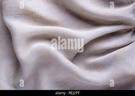 Soft folds of a light pink synthetic fabric texture with yellow gold ornaments to be used as background Stock Photo