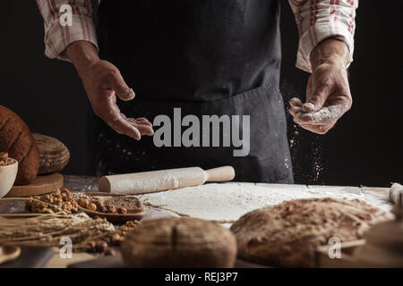 Man sprinkling some flour on dough. Hands kneading dough, cropped view Stock Photo
