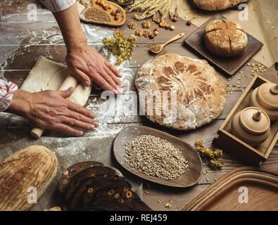 Man rolling out dough on kitchen table, close up Stock Photo