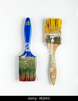 Two old dirty wooden paintbrushes with yellow and brown paint stains on white in a DIY, renovations, interior decorating, or maintenance concept Stock Photo