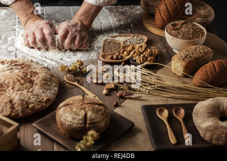 Close up of baker hands kneading dough and making bread with a rolling pin. Stock Photo