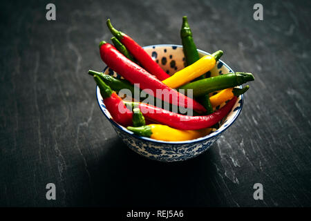 several fresh and colorful chili peppers in a bowl Stock Photo
