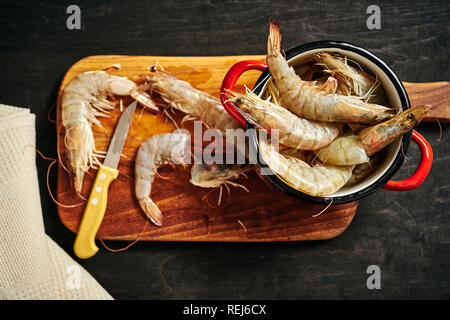 fresh, delicious raw tiger prawns prepared and cut on a wooden board Stock Photo