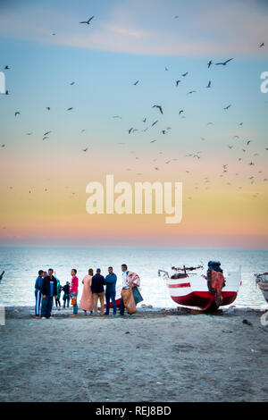 Oued Laou, Chefchaouen, Morocco - November 3, 2018: sunset with hundreds of seagulls flying over the fishermen and boats on the beach of Oued Laou. Stock Photo