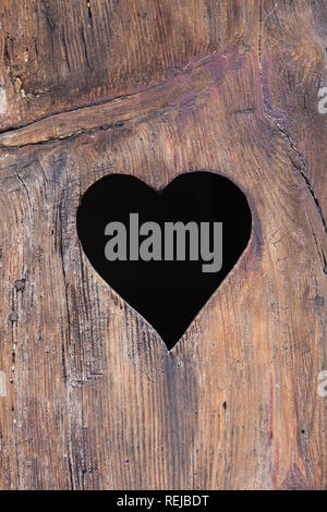 Charming heart shaped peep hole or aperture cut into front panel of old solid wooden door on house in Seillans, Provence-Alpes-Côte d'Azur, France. Stock Photo