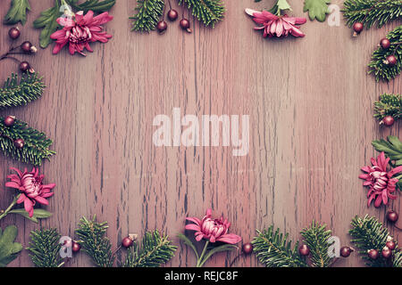 Burgundy chrysanthemum flowers on  textured background with fir twigs and berries, top view with copy-space Stock Photo