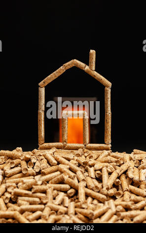 Miniature house made with wood pellets. Heating concept with combustion chamber in the background. Stock Photo