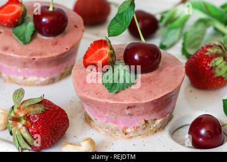 raw strawberry and cherry cakes with fresh berries, mint, nuts. healthy vegan food concept