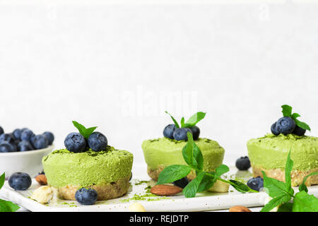 green matcha vegan raw cakes with blueberries, mint and nuts. healthy delicious food. close up Stock Photo
