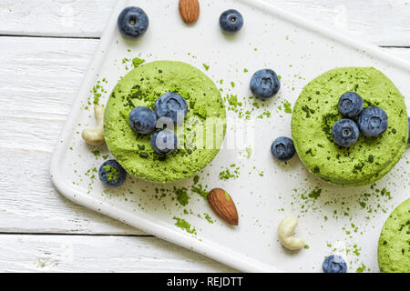 green matcha vegan raw cakes with blueberries, mint and nuts. healthy delicious food. top view Stock Photo