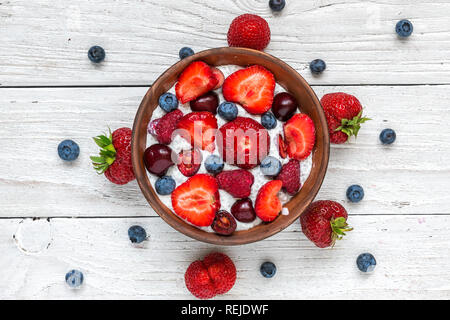 homemade berry yogurt or chia pudding with fresh raspberries, strawberries, cherry and blueberries in a bowl. healthy breakfast. top view Stock Photo
