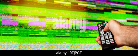 Man with large tv remote trying to fix the digital television noise on a large plasma OLED 4K Ultra HD High Dynamic Range HDR Smart TV flare Stock Photo