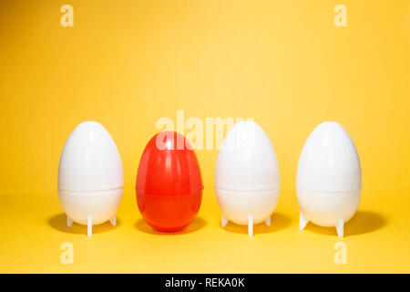 Difference concept. Four eggs on yellow. One red and three white plastic eggs on yellow background Stock Photo