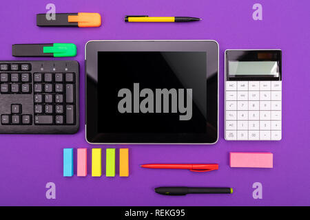 Modern workspace with tablet, keyboard and calculator on purple background. Flat lay concept Stock Photo