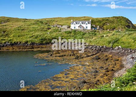 View of a traditional cottage by the sea at low tide on a beautiful summer day, Isle of Scalpay, Outer Hebrides, Scotland, UK Stock Photo