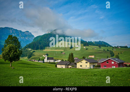 Landscape panorama of green nature and village houses near Appenzell, Alpstein mountains, Switzerland. Taken in June, in summer.