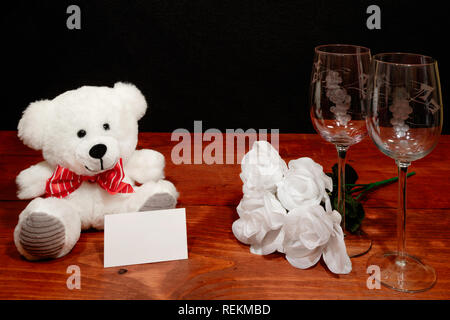 https://l450v.alamy.com/450v/rekmbd/beautiful-etched-wine-glasses-with-white-roses-and-white-teddy-bear-and-name-tag-on-wooden-table-and-dark-background-valentines-mothers-day-easter-rekmbd.jpg