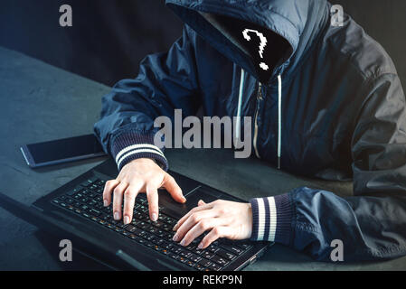Anonymous hacker programmer uses a laptop to hack the system. Stealing personal data. Creation and infection of malicious virus. The concept of cyber  Stock Photo