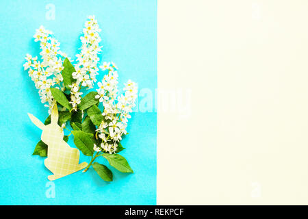 Easter bunny paper and spring flowers bird cherry trees. Minimal easter concept. Top view flat lay background. Stock Photo