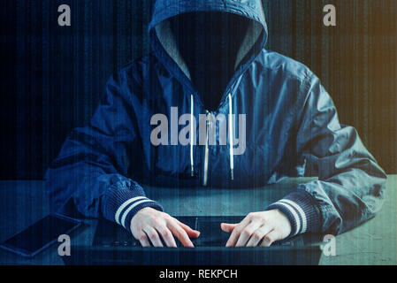 Anonymous hacker programmer uses a laptop to hack the system. Stealing personal data. Creation and infection of malicious virus. The concept of cyber  Stock Photo