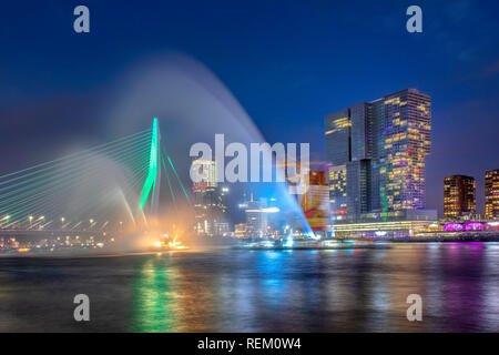 The Netherlands, Rotterdam, Port of Rotterdam. Skyline of city center, also called Kop Van Zuid. Erasmus bridge. Long exposure. Fireboat demonstration Stock Photo