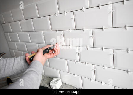 Ceramic tile lying. Installing new subway or metro tile in bathroom, shower or kitchen back splash during home renovation. Placing or taking out tile Stock Photo