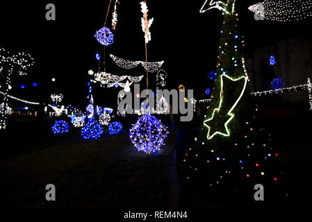 Glowing snowflakes and light stripes on dark, romantic night sky background. Beautiful Christmas market and decorations in city center. Stock Photo