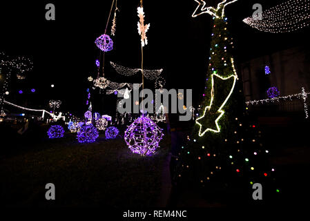 Glowing snowflakes and light stripes on dark, romantic night sky background. Beautiful Christmas market and decorations in city center. Stock Photo