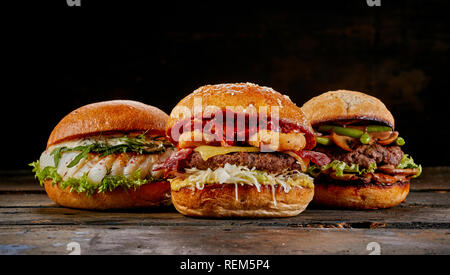 Selection of three different gourmet burgers with a fish seafood burger, surf and turf with bacon and squid and avocado and guacamole burger Stock Photo