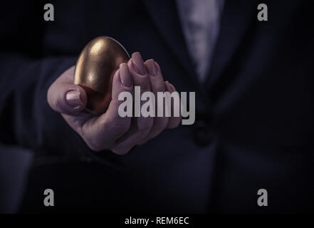 golden chicken egg in female hand closeup Stock Photo