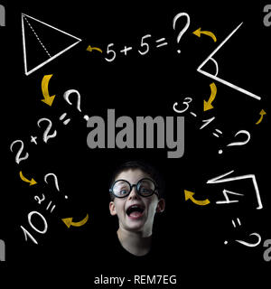 boy solve mathematics examples at the blackboard on black background ...