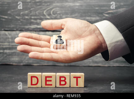 Wooden blocks with the word debt and the image of dollars. Payment of taxes and of debt to the state. Concept of financial crisis and problems. Risk m Stock Photo