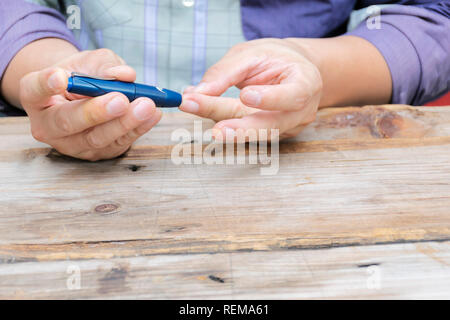 Man taking blood sample with lancet pen. Diabetes concept. Medicine, Diabetes, Glycemia, Health care and people - close up using lancelet on finger to Stock Photo