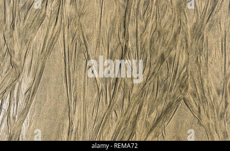 Traces of retracting water on sandy beach texture pattern. Pattern of waves left in the wet sandy beach background photo. Stock Photo