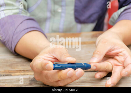 Man taking blood sample with lancet pen. Diabetes concept. Medicine, Diabetes, Glycemia, Health care and people - close up using lancelet on finger to Stock Photo