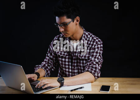 Programmer in the office working on the computer on a wooden desk Stock Photo