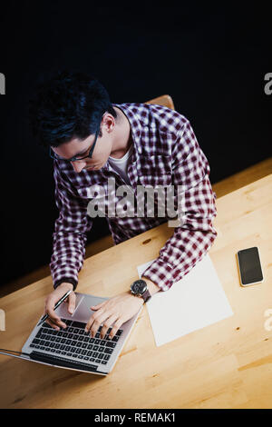 Programmer in the office working on the computer on a wooden desk Stock Photo