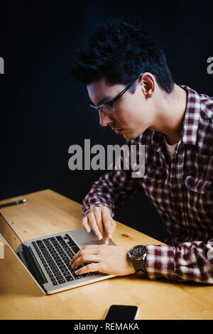 Programmer in the office working on the computer on a wooden desk Stock Photo