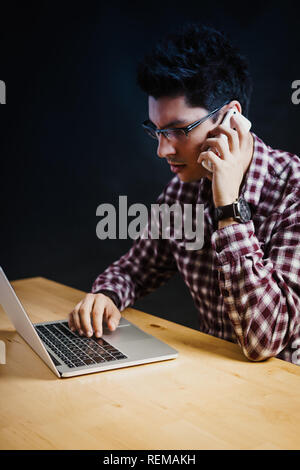 Programmer in the office working on the computer on a wooden desk Stock Photo