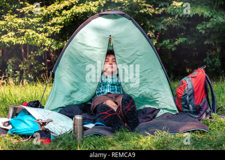 Spending a vacation on camping. Young man resting in a tent Stock Photo