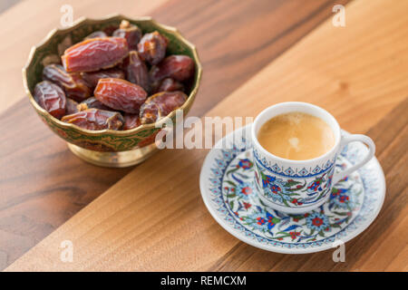 Turkish coffee and dates in cup on brown wooden table Stock Photo